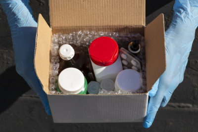 Box of medicine as a pharmacy delivery. Hands in blue medical gloves hold a box with medicines.